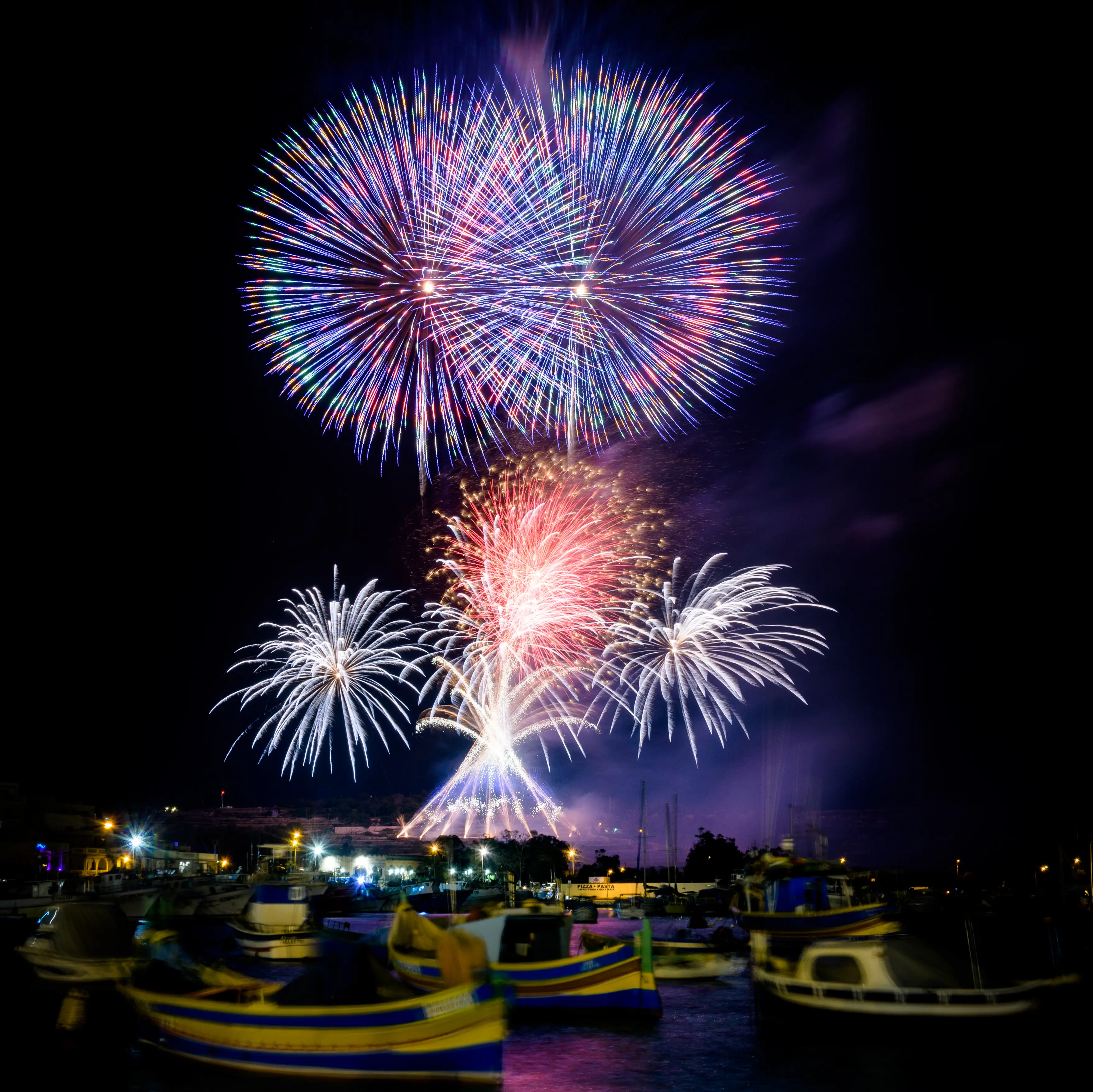 Festa Fireworks A candid shot taken during a traditional Maltese festa, capturing sparkling fireworks reflecting across the sea.