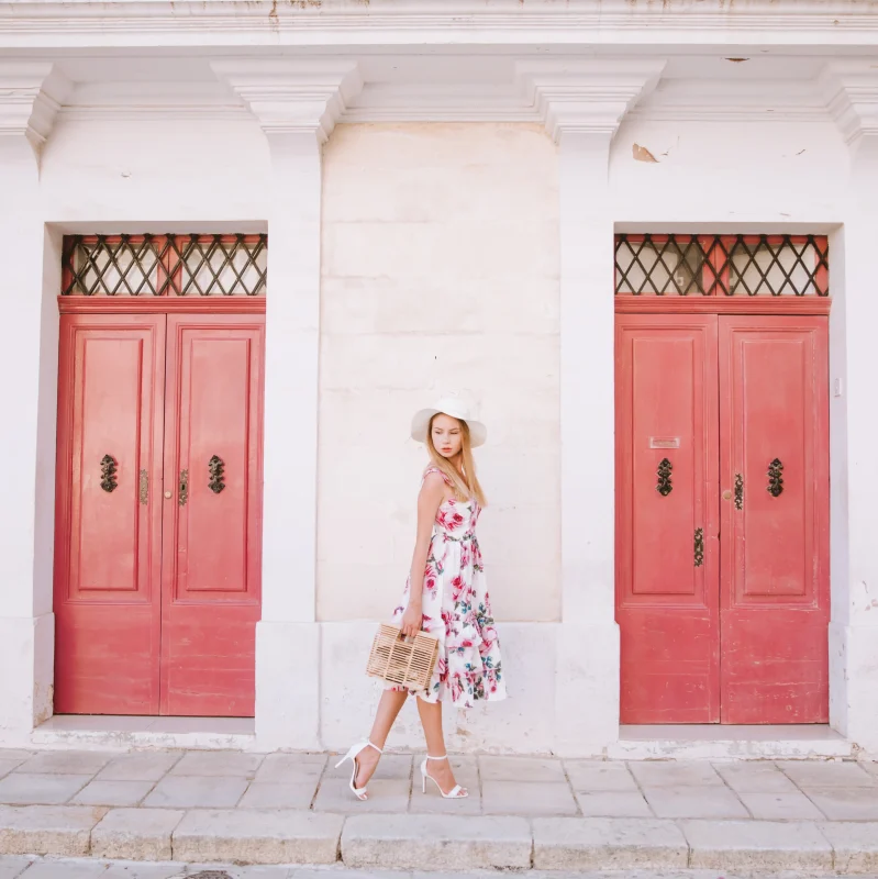 A picture of a woman posing in front of Maltese doors in a road in Mdina.