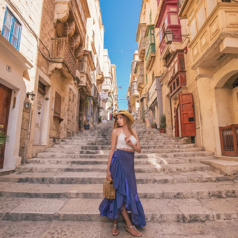 Woman posing in front of a typical Valletta street made up entirely of stairs. A popular Malta holiday photo.