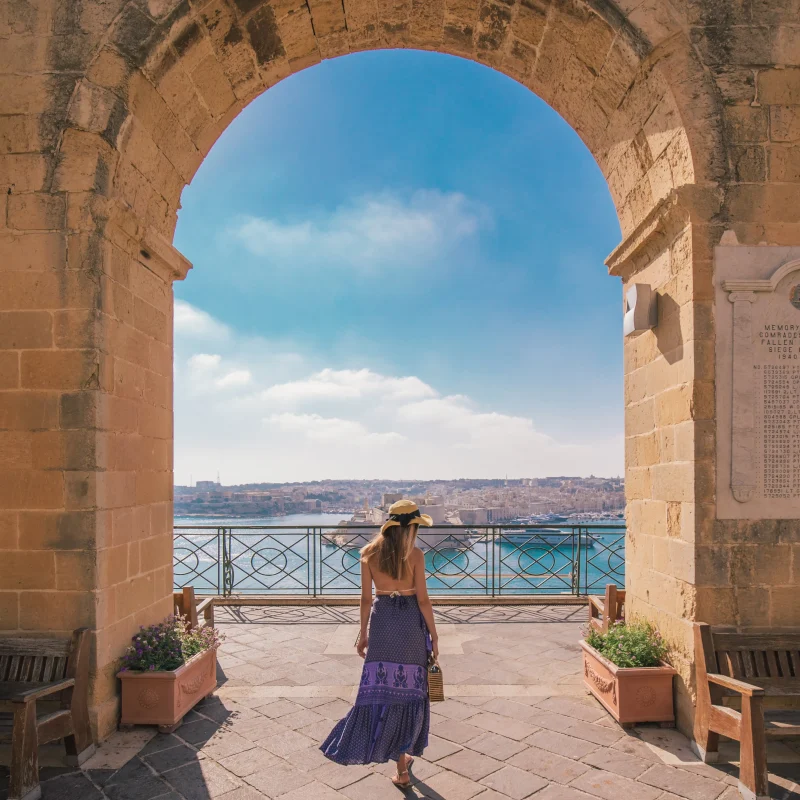 Woman posing beneath an arch in the Upper Barrakka Gardens, Valletta.