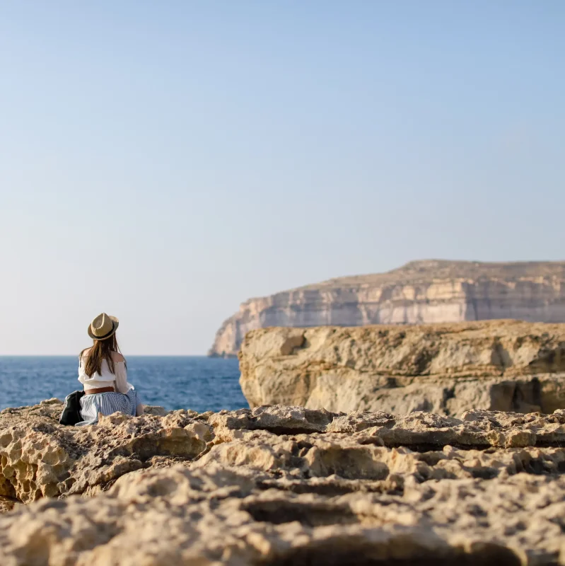 A woman enjoying a view of the Maltese coastline whilst soaking in the sun and sea.